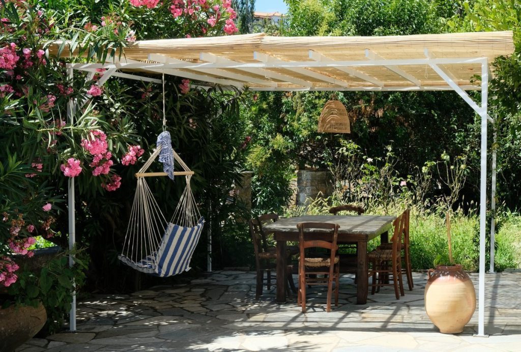 Pergola with table and hanging chair. Enjoy your vacations in Greece by staying in a beautiful cottage near Lafkos village square in the fabulous nature of South Pelion.