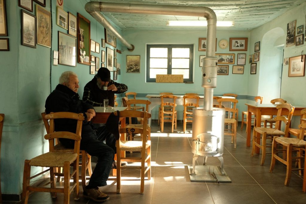 People wait for the time to pass in the oldest coffee shop in Greece. Lafkos, the mountain village near the sea, is one of the most beautiful and authentic places on the Greek peninsula of Pelion, characterized by an atmospheric square and the absence of cars. Vacation home in Pelion. Holidays in Greece.