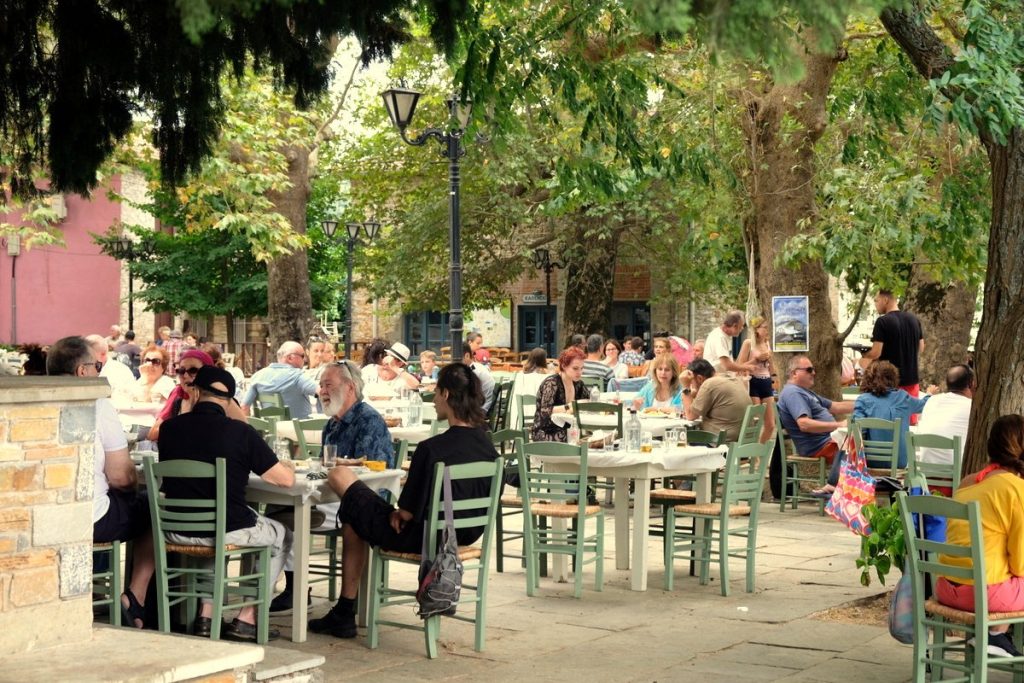 Lafkos square with restaurants and people. Enjoy one of the most beautiful and authentic mountain villages in Greece.